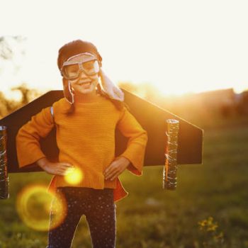 Child pilot aviator with wings of airplane dreams of traveling in summer in nature at sunset